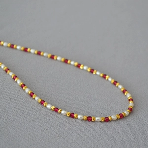 Detail of elegant beaded necklace with natural pearls and red faceted corundum beads