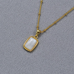 Detail of gold-plated brass necklace featuring a rectangular moonstone pendant on a beaded chain