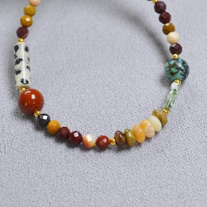 Détail de perles en pierres naturelles multicolores avec intercalaires dorés sur maille