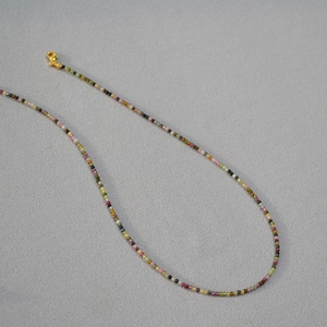 Macro detail of 2mm colorful tourmaline beads and golden lobster clasp necklace