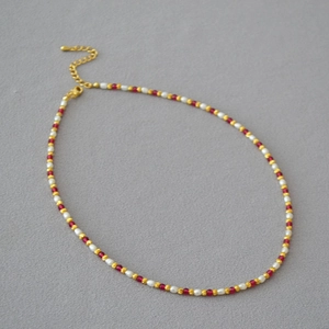 Detail of elegant beaded necklace with red corundum, pearls, and gold-plated lobster clasp