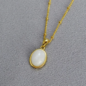 Minimalist gold necklace with a white oval natural stone pendant on a beaded chain