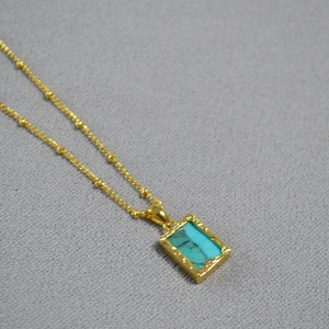 Detail of vintage gold necklace with turquoise stone inlay and beaded chain textures
