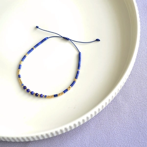 Close-up of bohemian blue beads and gold spacers on an adjustable braided cord bracelet