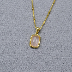 Macro detail of gold-plated necklace with a rectangular pink stone pendant