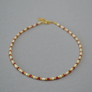 Close-up of elegant rice pearl and red corundum beaded necklace with golden clasp