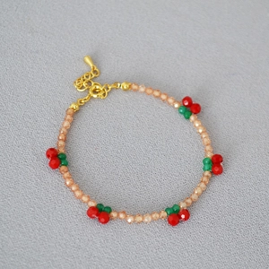Detail of beaded bracelet featuring red cherry charms and champagne crystal beads