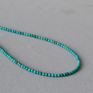 Macro detail of turquoise beaded necklace showing natural stone texture and blue-green hues