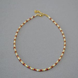 Detailed view of red corundum beads and imitation pearls with a gold lobster clasp