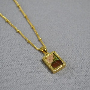 Close-up of a gold rectangle pendant necklace with natural stone in a vintage design