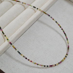 Macro detail of fine 2mm colorful natural tourmaline beads on a minimalist necklace