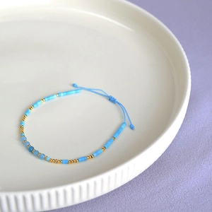Detail of bohemian handmade beaded bracelet with light blue beads and adjustable knot strap