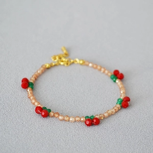 Detailed view of handmade beaded bracelet with champagne crystals and red cherry charms
