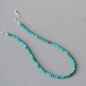 Minimalist turquoise beaded necklace with adjustable silver lobster clasp on grey background