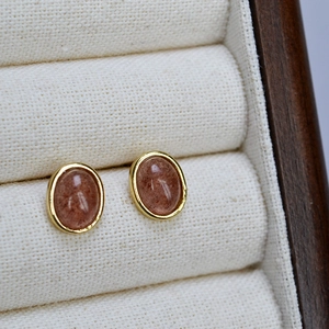 Macro view of gold plated brass earrings with oval natural gemstone in a jewelry box