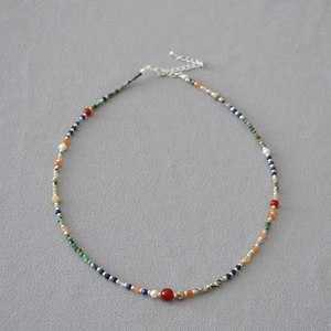 Detail of beaded necklace with lapis lazuli, freshwater pearls, and red agate gems