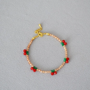 Detail of handmade beaded bracelet with red cherry charms and champagne crystals