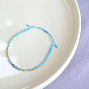 Detail of adjustable blue beaded bracelet with gold spacers and knotted closure