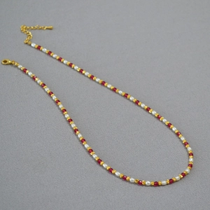Detail of red bead and pearl necklace with golden lobster clasp and extender chain
