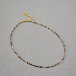 Detailed close-up of 2mm multi-colored tourmaline beaded necklace with gold lobster clasp