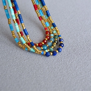 Close-up of bohemian layered beaded necklaces with colorful stones on gray texture