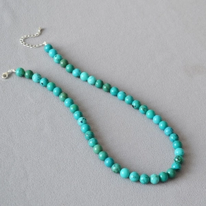 Detail of natural turquoise bead necklace showing unique texture and silver lobster clasp