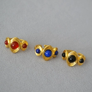 Detail view of retro gold-plated rings with red blue and black gemstone inlays