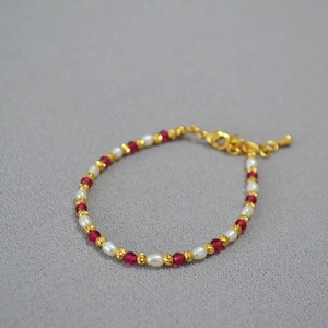 Detail of beaded necklace with white pearls, red crystals and gold-tone clasp