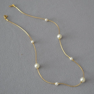 Detailed view of elegant white pearls on a minimalist golden snake chain necklace