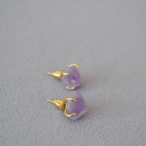 Detailed view of raw purple amethyst studs with gold four-prong setting for women