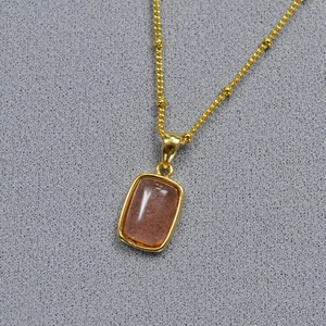 Close-up of gold-plated brass necklace with rectangular orange gemstone pendant