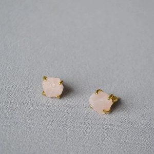 Detail of pink raw gemstone earrings with gold-plated four-prong setting and unique texture