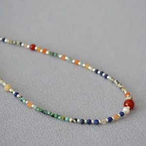 Macro detail of handmade necklace featuring turquoise, lapis lazuli and pearls