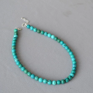 Detail of turquoise beaded necklace with silver lobster clasp and extension chain texture
