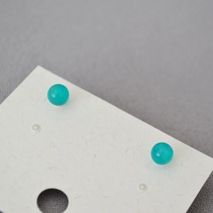 Macro shot of turquoise blue spherical stud earrings on a textured display card