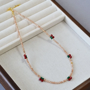 Close-up of champagne zircon beaded necklace with cherry charms in a jewelry box