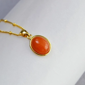 Detailed macro view of an oval orange agate pendant with a polished gold bezel setting