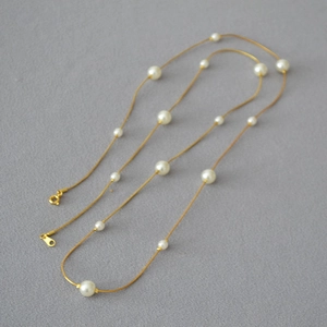 Detail of elegant gold snake chain with white pearls and adjustable lobster clasp
