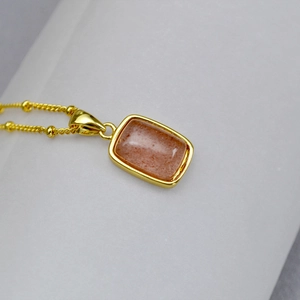 Detail of a vintage brass necklace featuring a rectangular red stone with gold-plated edges