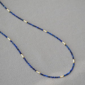 Macro view of dainty lapis lazuli beads with pearls and gold accents on fine necklace