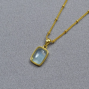 Macro detail of gold-plated brass necklace with a rectangular blue gemstone pendant
