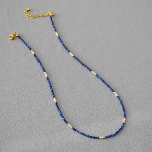 Macro shot of lapis lazuli beaded necklace with pearls and gold plated lobster clasp