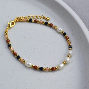 Close-up of baroque pearl bracelet with gold beads and faceted gemstones on ceramic tray