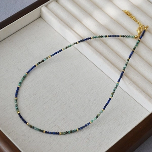 Handmade beaded necklace with turquoise and lapis lazuli stones on a white velvet tray