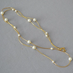 Close-up of double-layer gold snake chain with white pearls and lobster clasp