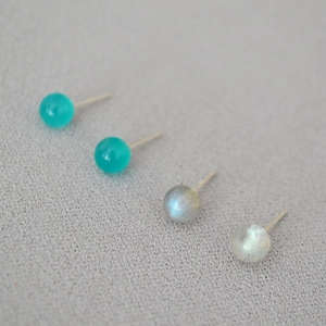 Macro detail of four small ball stud earrings with labradorite and amazonite stones