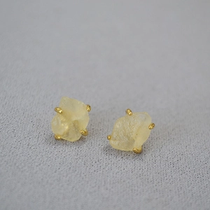 Macro shot of irregular yellow raw gemstones secured in gold-plated four-prong stud settings