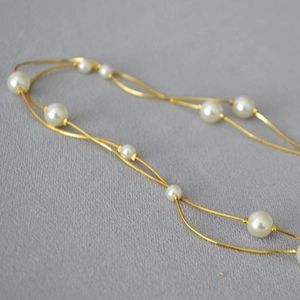 Elegant double-layer gold snake chain necklace with white pearls on grey background
