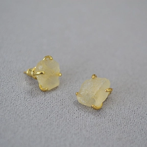 Detailed close-up of yellow raw gemstone stud earrings with four-prong gold-plated setting