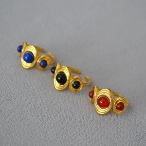 Detail of vintage gold-plated rings with blue black and red round agate inlay